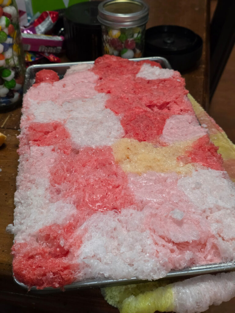 a tray that has just become a multicolored solid sheet of delicate sugar product. it kind of looks like a patchwork quilt where the different color starburst merged together