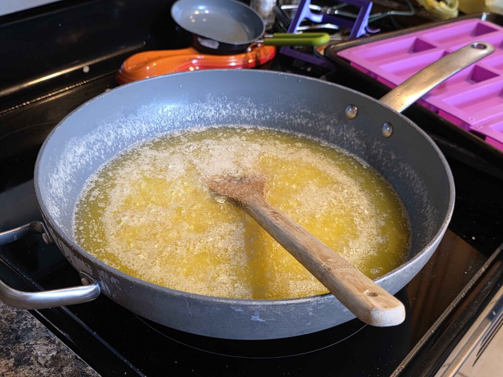 A huge sauce pan that almost looks like a wok full of melted butter.