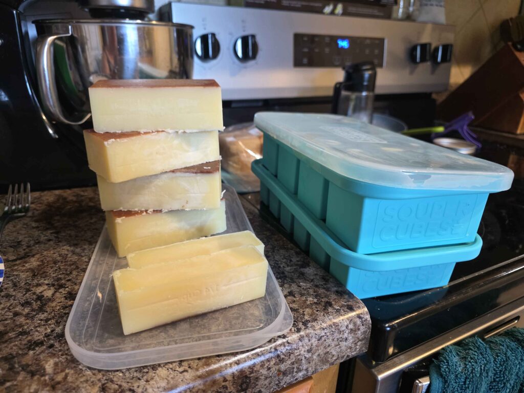 Two souper cube trays next to the butter I've removed. You can see the brown bits on the top because they sink to the bottom while chilling.