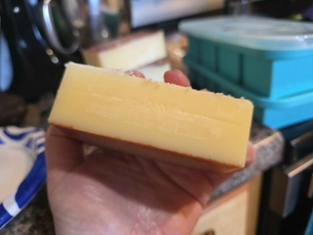 My hand holding a one cup stick of brown butter.