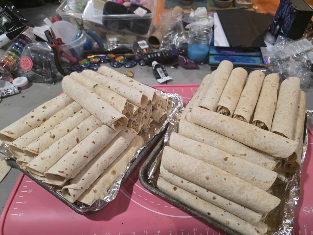 a cookie tray stacked high with taquitos freshly rolled
