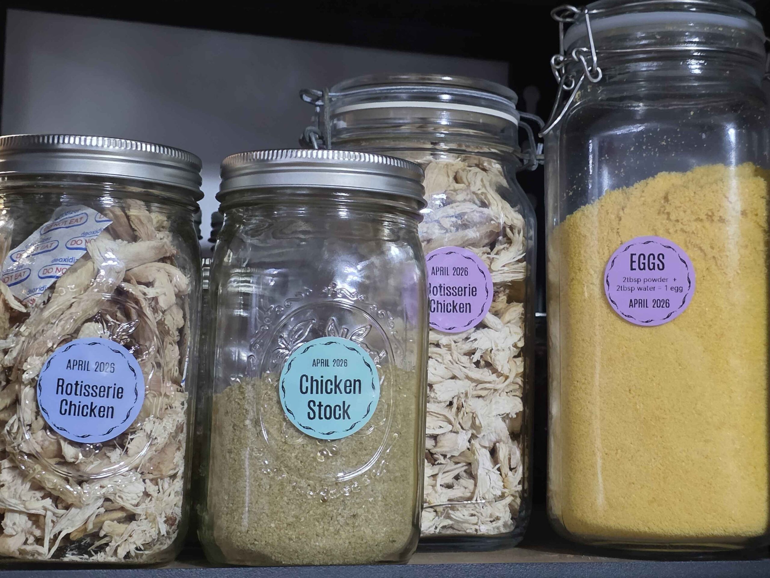 A shelf in my garage with 4 jars: two large ones with eggs and chicken, and two quart jars with  more chicken, and my chicken stock.