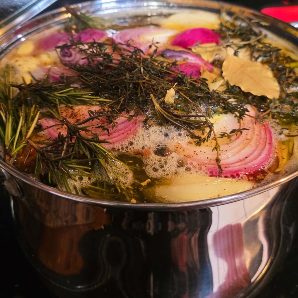 a close up of a large stock pot full of onions and herbs floating on the top. very artistic, Mr. Bree